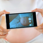 Pregnant woman taking a photo of her belly.
